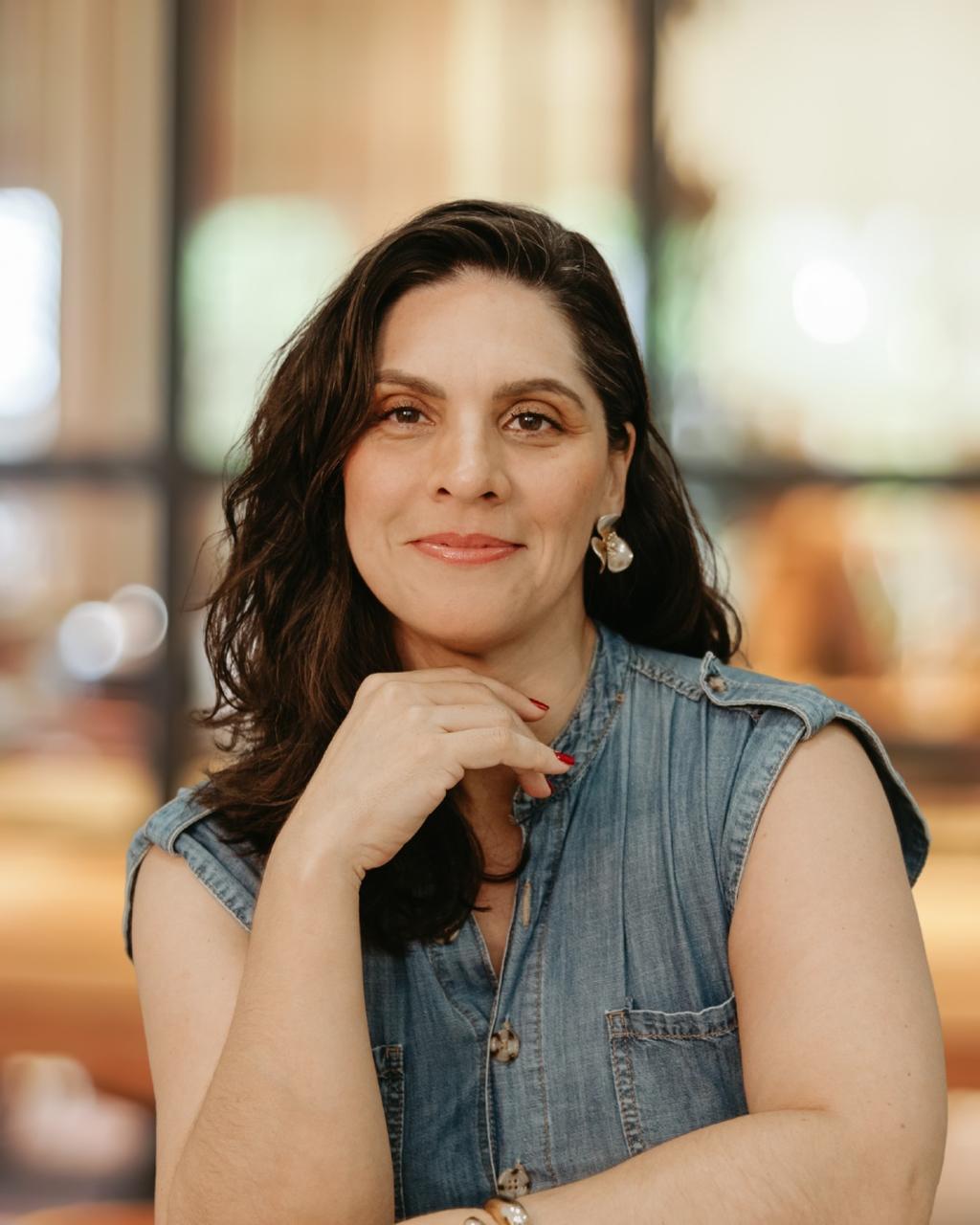 Thelma Taborda com o rosto apoiado na mão — fotografia oficial